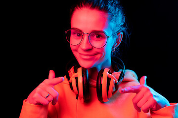 Image showing Fashion pretty woman with headphones listening to music over neon background