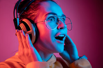 Image showing Fashion pretty woman with headphones listening to music over neon background