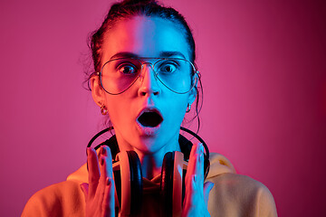 Image showing Fashion pretty woman with headphones listening to music over neon background