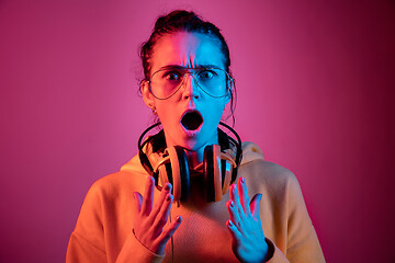 Image showing Fashion pretty woman with headphones listening to music over neon background