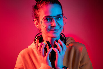 Image showing Fashion pretty woman with headphones listening to music over neon background