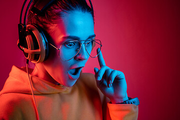 Image showing Fashion pretty woman with headphones listening to music over neon background