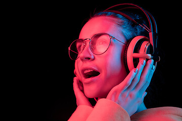 Image showing Fashion pretty woman with headphones listening to music over neon background