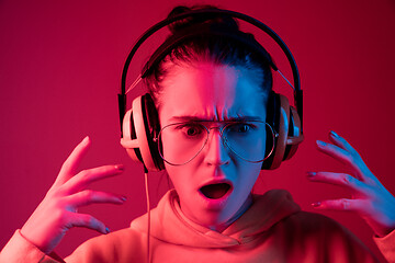 Image showing Fashion pretty woman with headphones listening to music over neon background