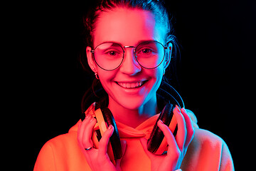 Image showing Fashion pretty woman with headphones listening to music over neon background