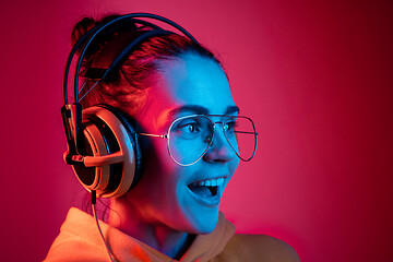 Image showing Fashion pretty woman with headphones listening to music over neon background