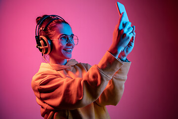 Image showing Fashion pretty woman with headphones listening to music over neon background