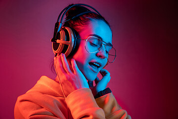 Image showing Fashion pretty woman with headphones listening to music over neon background