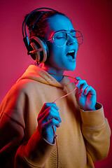 Image showing Fashion pretty woman with headphones listening to music over neon background