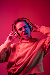 Image showing Fashion pretty woman with headphones listening to music over neon background