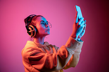 Image showing Fashion pretty woman with headphones listening to music over neon background