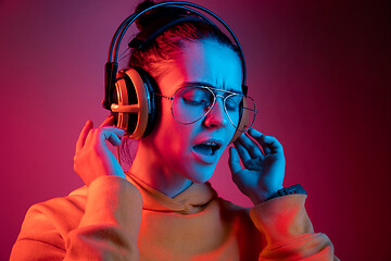 Image showing Fashion pretty woman with headphones listening to music over neon background