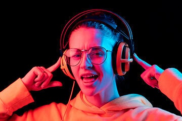 Image showing Fashion pretty woman with headphones listening to music over neon background