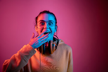 Image showing Fashion pretty woman with headphones listening to music over neon background