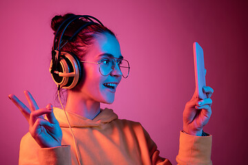 Image showing Fashion pretty woman with headphones listening to music over neon background