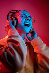 Image showing Fashion pretty woman with headphones listening to music over neon background