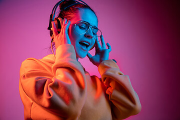 Image showing Fashion pretty woman with headphones listening to music over neon background