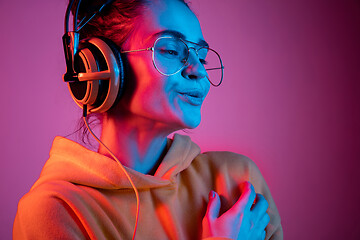 Image showing Fashion pretty woman with headphones listening to music over neon background