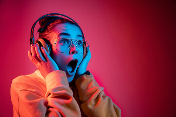 Image showing Fashion pretty woman with headphones listening to music over neon background