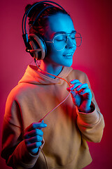 Image showing Fashion pretty woman with headphones listening to music over neon background