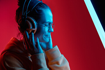 Image showing Fashion pretty woman with headphones listening to music over neon background