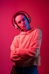 Image showing Fashion pretty woman with headphones listening to music over neon background