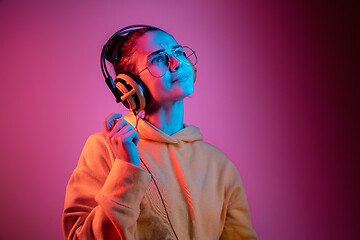 Image showing Fashion pretty woman with headphones listening to music over neon background