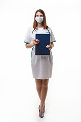 Image showing girl doctor in medical clothes and mask with tablet in hand on white background