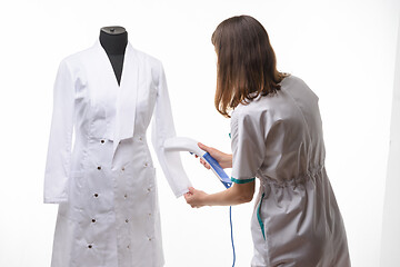 Image showing Girl in medical clothes handles steam clothes on manicure