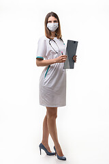 Image showing girl doctor in medical clothes and mask with tablet in hand on white background builds in full growth