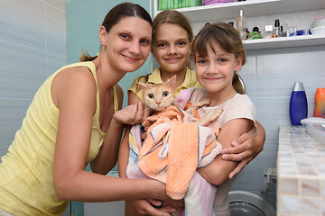 Image showing Family poses in the bathroom with wet bathed cat wrapped in towel