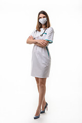 Image showing A girl in medical clothes stands folded her arms on her chest in full height on a white background