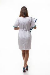 Image showing A girl in medical clothing stands back nwa back background