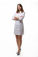 Image showing A girl in white uniform stands with her arms folded on her chest against a white background