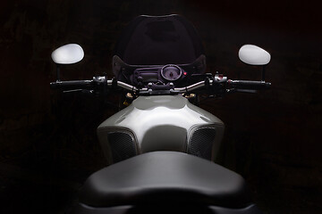 Image showing Custom caferacer motorbike on dark background with its headlight on.