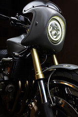 Image showing Custom caferacer motorbike on dark background with its headlight on.