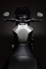 Image showing Custom caferacer motorbike on dark background with its headlight on.