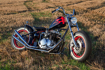 Image showing Custom bobber motorbike standing in a wheat field.