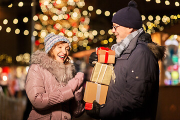 Image showing happy senior couple with gift at christmas market