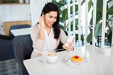 Image showing asian woman with smartphone and earphones at cafe