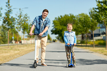 Image showing father and little son riding scooters in city