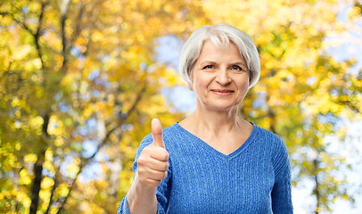 Image showing senior woman r showing thumbs up in autumn park