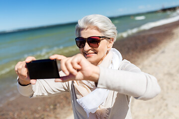 Image showing senior woman taking selfie by smartphone on beach