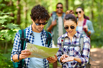 Image showing friends with map and backpacks hiking in forest