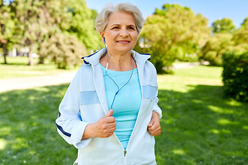 Image showing senior woman with earphones running in summer park