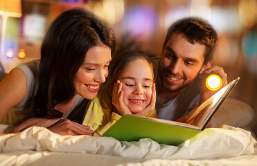 Image showing happy family reading book in bed at night at home
