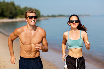 Image showing couple in sports clothes running along on beach