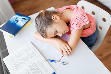 Image showing tired student girl sleeping on table at home