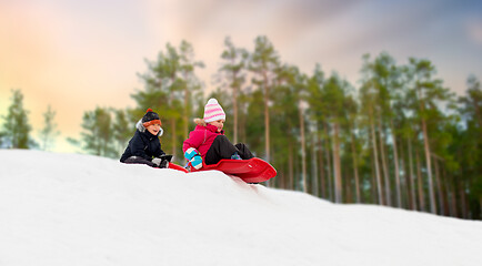 Image showing happy kids sliding on sleds down hill in winter