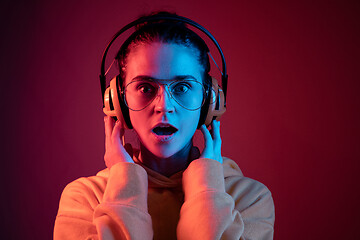 Image showing Fashion pretty woman with headphones listening to music over neon background